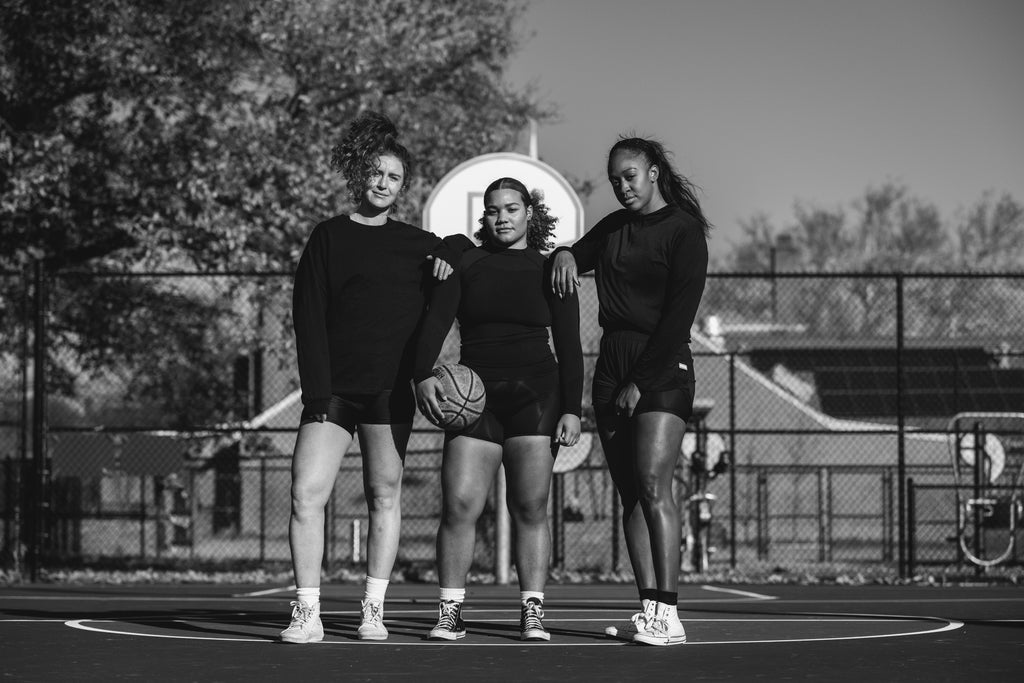three strong, athletic female athletes playing basketball on a basketball court, white woman, two black women